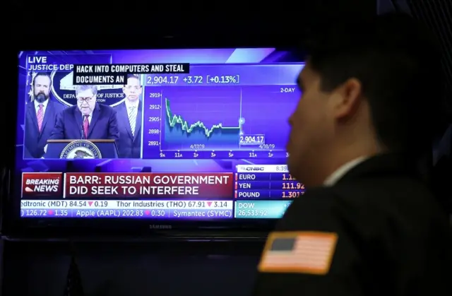 A trader at the New York Stock Exchange watches the stock market as Barr speaks