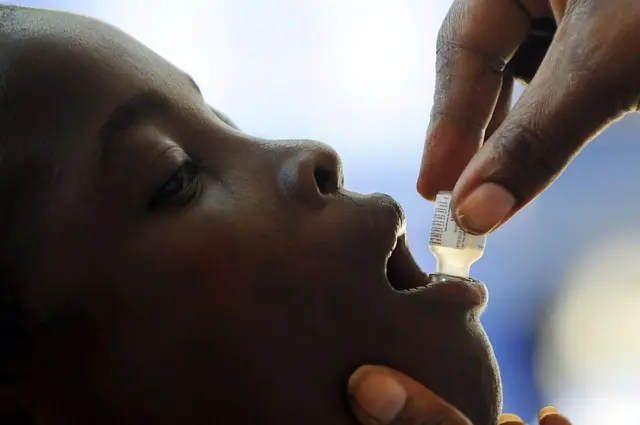 A boy given given an oral dose of the anti-Cholera vaccine by a medical professional.