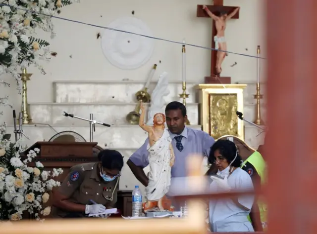 Police officer inspect damage to a statue of Jesus