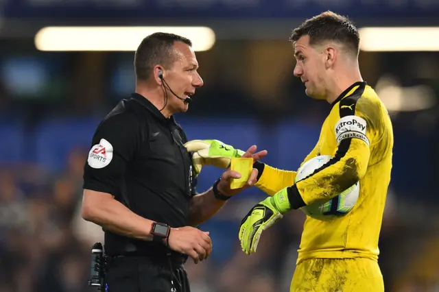 Referee Kevin Friend shows a yellow card to Burnley goalkeeper Tom Heaton