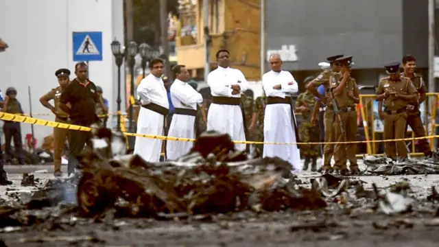 Sri Lankan priests look at the debris of a car after it explodes near St Anthony's Shrine in Colombo