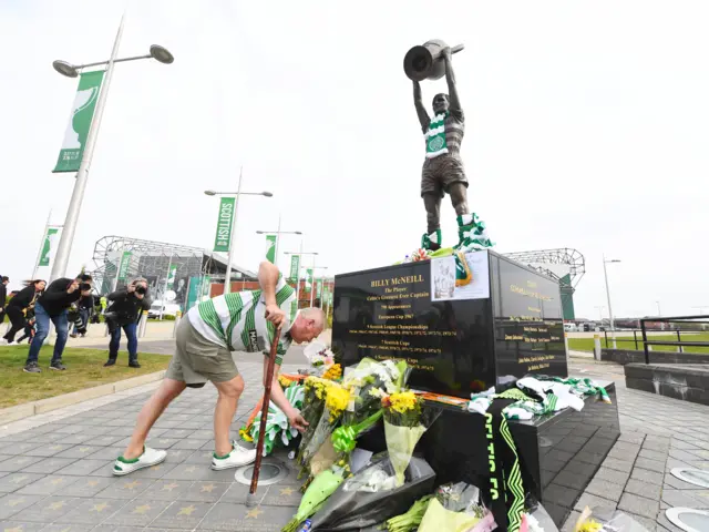 A Celtic fans lays flowers at Billy McNeill's statue