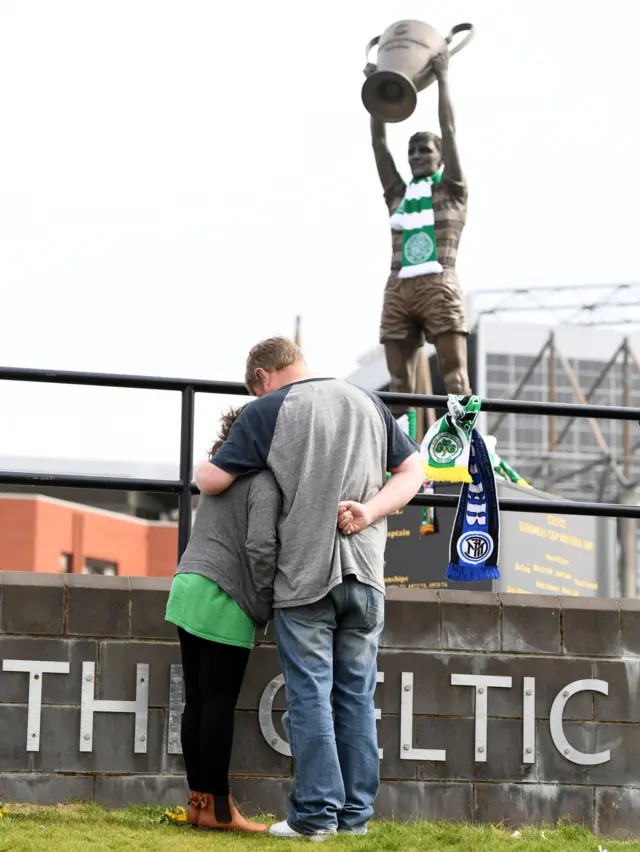 Fans console one another at Billy McNeill's statue