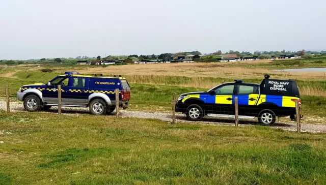 Coastguard and bomb squad vehicles at the beach