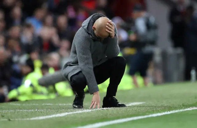 Pep Guardiola kneels down on touchline with his head in his hands