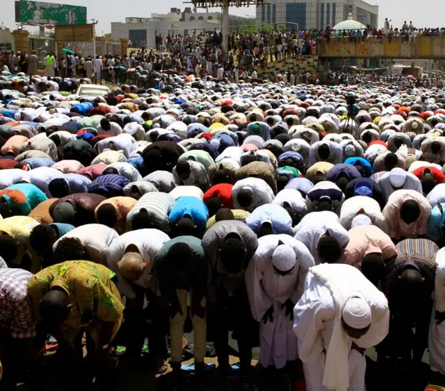 Imams and protesters bow in prayer outside