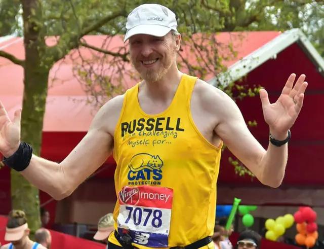 Russell poses looking happy in his running top and baseball cap.