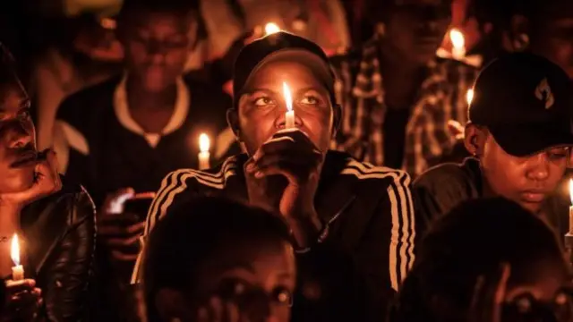 People hold candles in remembrance at a vigil at Amahoro Stadium