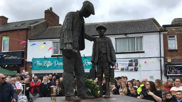 Onlookers view the Da Said "Men Don't Cry" statue