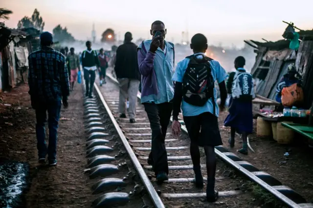 Kenyan youth walk along a rail track as they make their way to school in Kibera, a slum neighbourhood some five kilometres from Nairobi city centre, on March 14, 2017