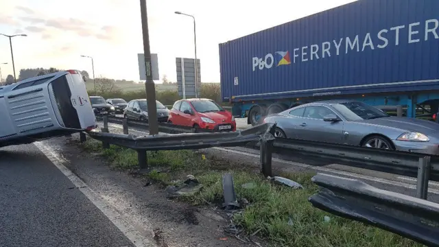 Over turned car on the central reservation and traffic delays