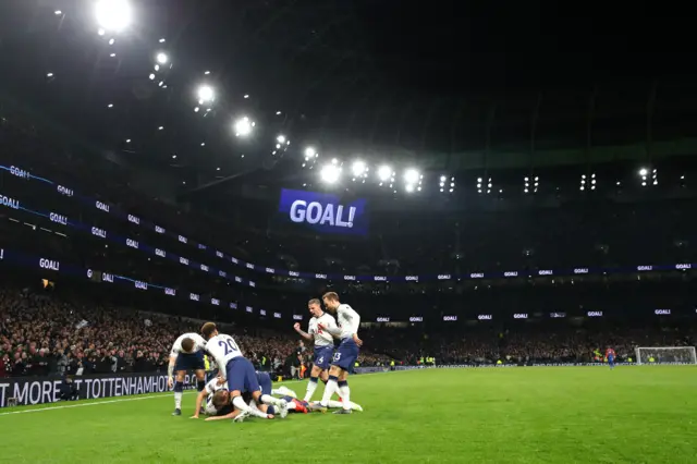 Son is mobbed by Spurs team-mates after scoring the opening league goal at the new Tottenham Hotspur Stadium