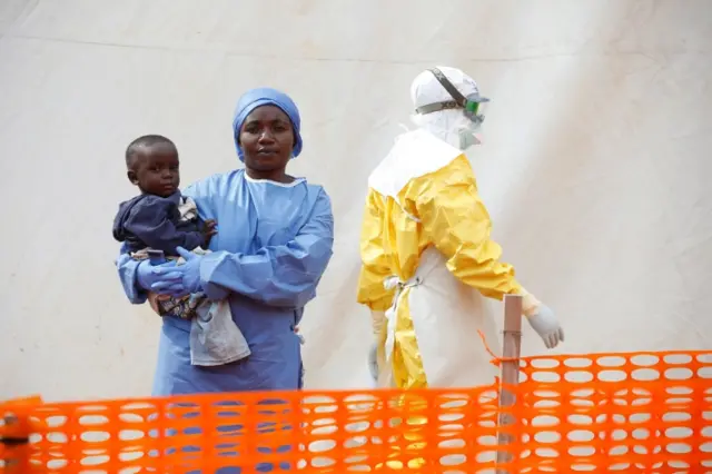 Mwamini Kahindo, an Ebola survivor working as a caregiver to babies who are confirmed Ebola cases, holds an infant outside the red zone at the Ebola treatment centre in Butembo,