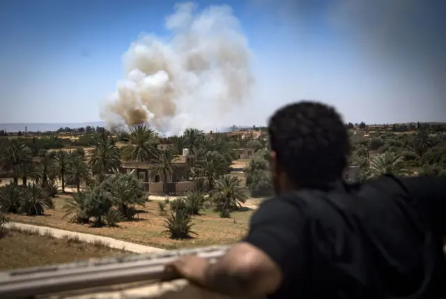 A fighter loyal to the internationally recognised Government of National Accord (GNA) watches as smoke rises in the distance during clashes with forces loyal to strongman Khalifa Haftar, in Espiaa, about 40 kilometres (25 miles) south of the Libyan capital, Tripoli, on 29 April 2019.