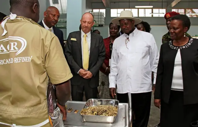 resident of Uganda Yoweri Museveni (C) flanked by Irene Muloni, Minister of Energy and Minerals Development (R) and Alain Goetz, CEO of AGR Limited (C,L) is shown gold flakes at the African Gold Refinery (AGR ltd) in Entebbe on February 20, 2017.