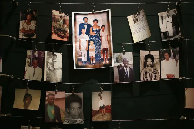 Individual photos of genocide victims, including a family, are displayed on a wall.