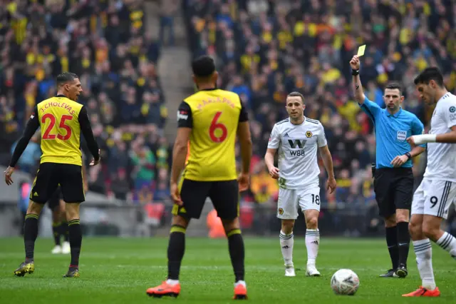 Michael Oliver (2nd R) shows a yellow card to Watford"s German-born Greek midfielder Jose Holebas