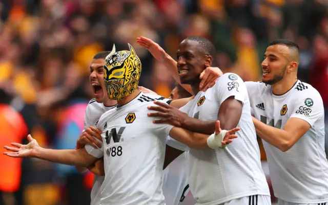 Raul Jimenez of Wolverhampton Wanderers wears a mask as he celebrates scoring his team"s second goal with team mayes Conor Coady, Willy Boly and Romain Saiss