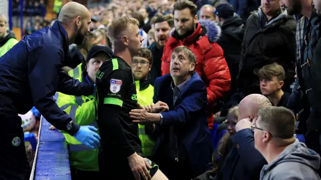 Nathan McGinley gets up among the Tranmere fans after falling over the advertising boards