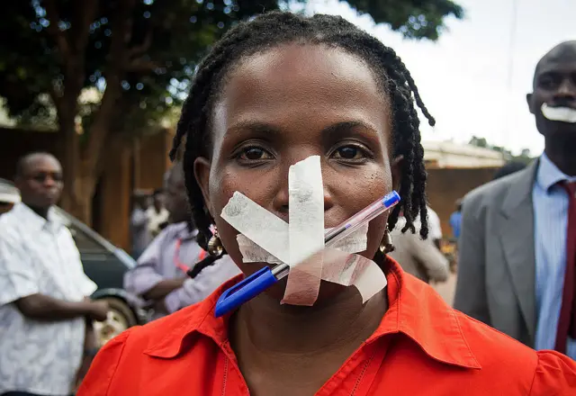 A journalist masks her mouth in protest