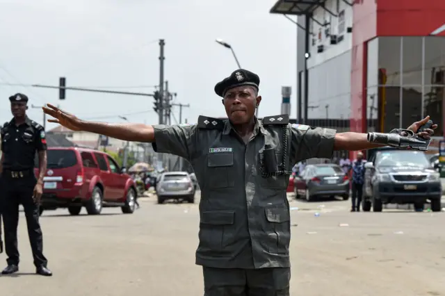 A policeman at Port Harcourt stretching his arms out to prevent protesters getting through.