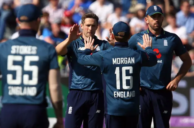 Chris Woakes (C) celebrates with team mates after taking the wicket of Pakistan"s Imad Wasim