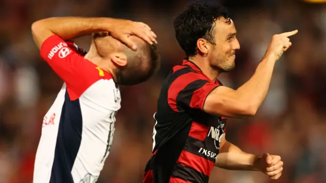 Mark Bridge of Western Sydney Wanderers celebrates scoring as Cameron Watson of Adelaide United feels the pain