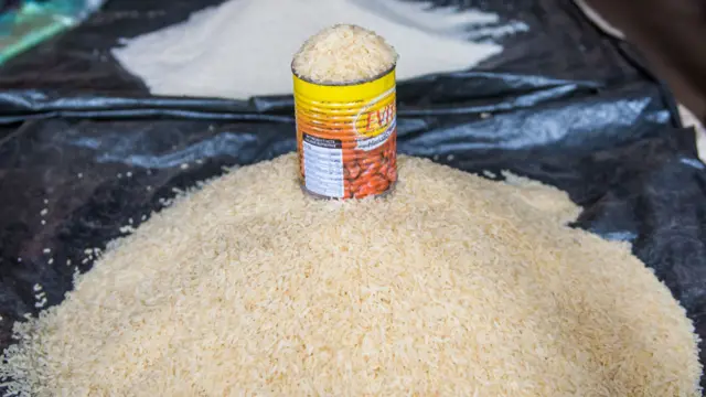 A can overflows with rice on top of a mound of rice