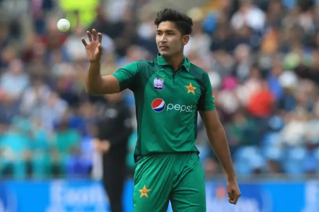 Mohammad Hasnain catches the ball as he prepares to bowl