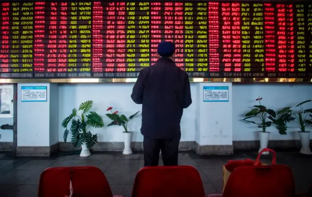 Man stands in front of stock market boards in Asia