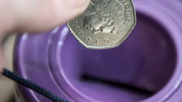 50p coin being dropped into charity container