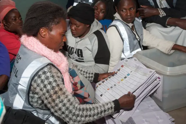 A presiding officer sorts ballot papers with polling staff and political parties monitors during vote counting at the Ndirande Community ground polling centre on May 21, 2019 in Blantyre, southern Malawi, during the country general elections