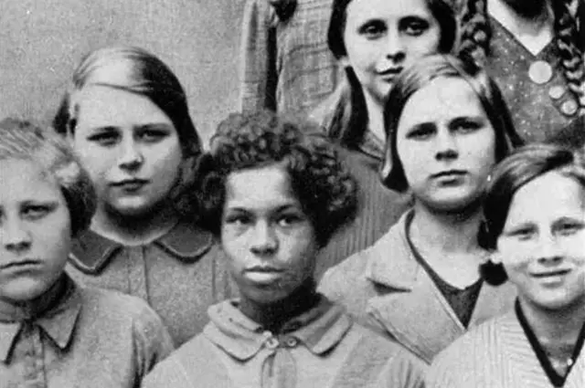 Photo showing a black girl among white pupils