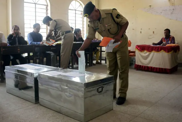 An Indian paramilitary force personnel, recruited for election duty during the upcoming elections, casts his vote in a ballot box.