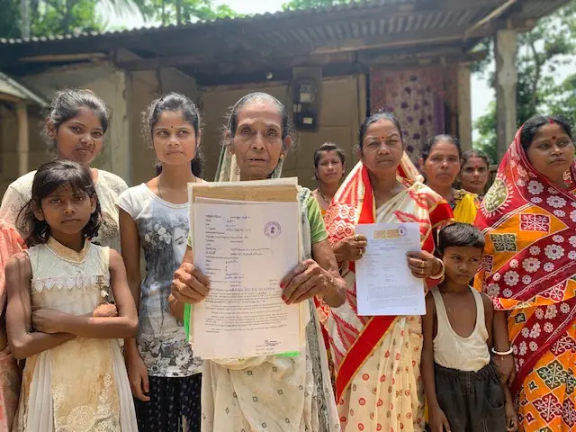 Women from an Assamese village hold up national identity papers.