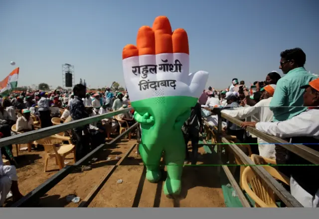 A supporter wearing an inflatable symbol of India"s main opposition Congress party walks during a public meeting in Gandhinagar, Gujarat.