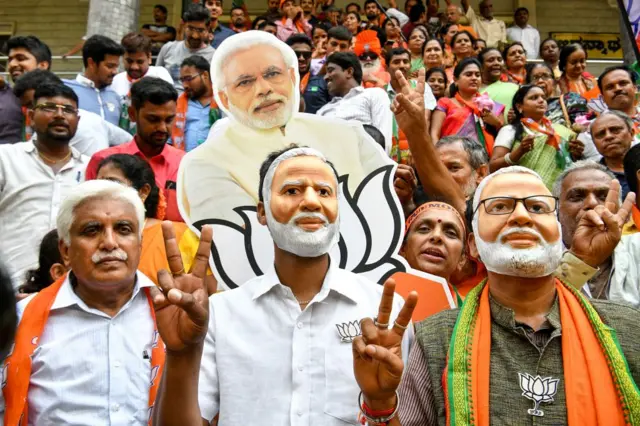 Indian supporters and party workers of Bharatiya Janata Party (BJP) wear masks of Indian Prime Minister Narendra Modi and flash victory signs as they celebrate on the vote results day for India's general election in Bangalore.