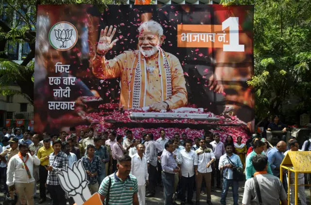 BJP supporters celebrate in front of a poster of Mr Modi.