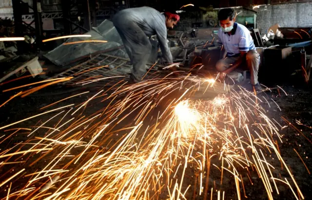 Indian labourers work at a metal factory