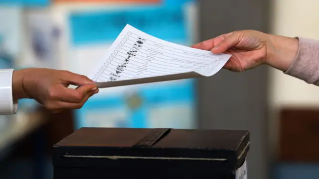 A man delivers a ballot paper to vote at a polling station in Lisbon, Portugal, 26 May 2019.