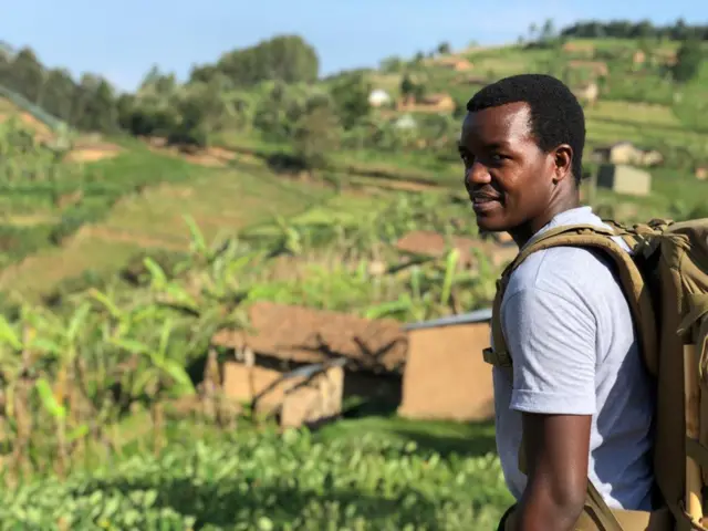 Hyppolite Ntigurirwa pictured walking across farmland with rucksack on his back