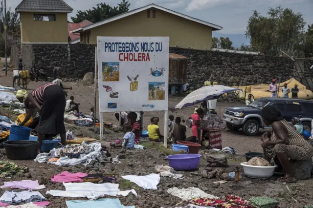 A woman desinfects vomit for cholera prevention between tents in camp Mugunga III for displaced persons on January 14, 2013 in Goma, Democratic Republic of Congo.