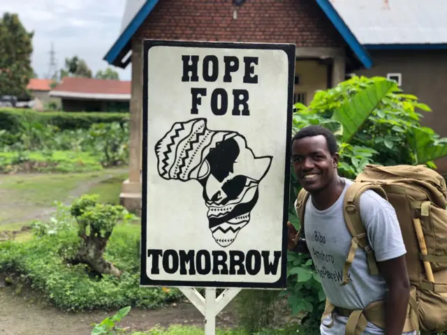 Hyppolite Ntigurirwa pictured next to a sign that reads 'Hope For Tomorrow'.