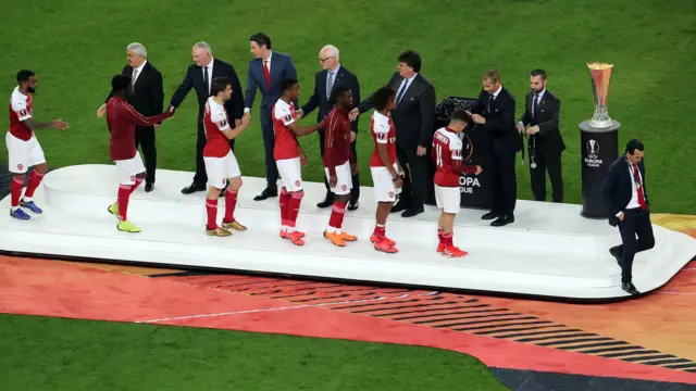 Unai Emery and Arsenal players walk past the Europa League trophy