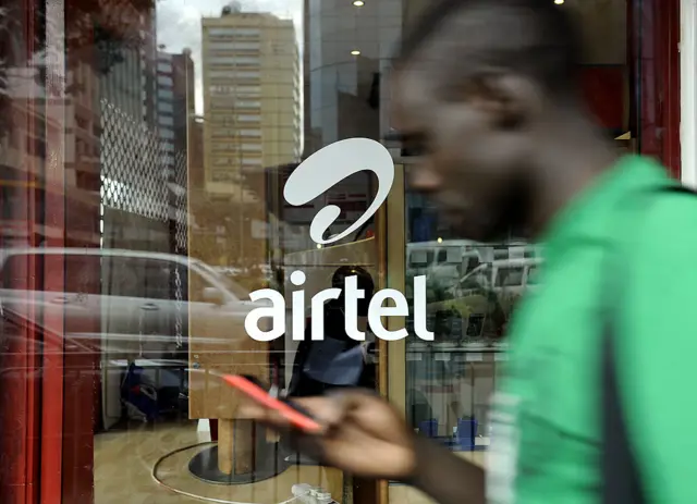 Man walking past Airtel sign