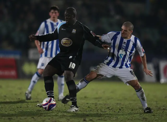 Northampton Town's Adebayo Akinfenwa holds off Brighton's Adam El Abd at the Withdean Stadium in a League One match in February, 2009