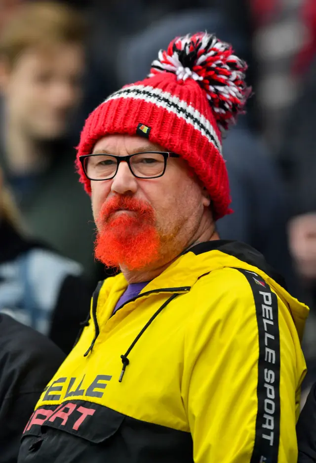 Manchester United fans looking unimpressed with a Utd bobble hat and red goatee beard