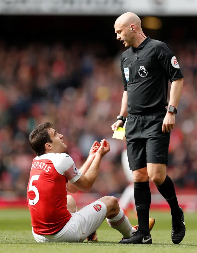Sokratis Papastathopoulos is shown a yellow card by referee Anthony Taylor for diving