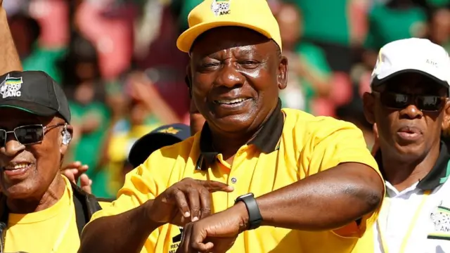 South Africa's Presdient Cyril Ramaphosa gestures to his wristwatch