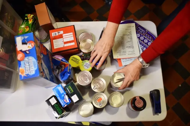 A volunteer selects food for a visitor's order at a food bank